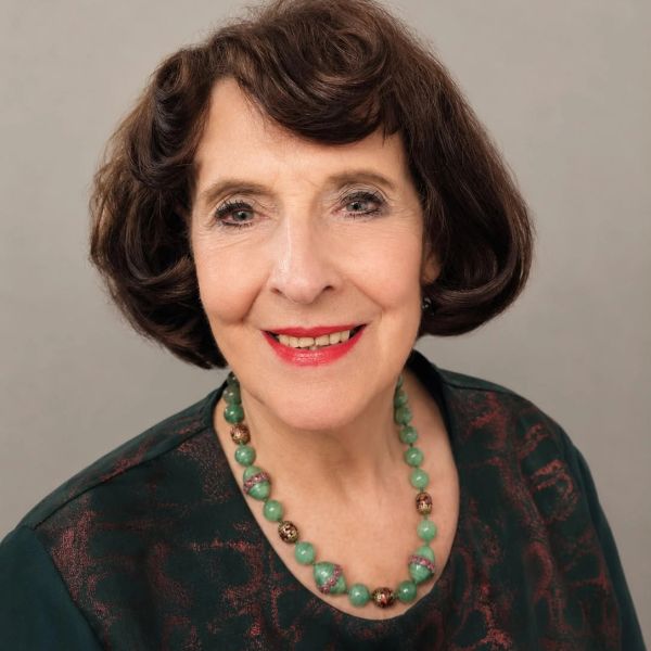 Elderly woman with short brown hair smiling.