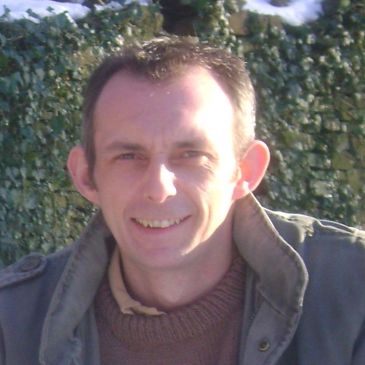 Smiling man outdoors in winter clothing.