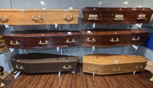 Six wooden coffins displayed on wall and floor.