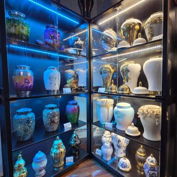 A museum display of various decorative urns and vases under blue and white lighting.