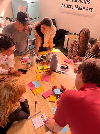 People gathered around a table with sticky notes and lollipops, engaged in discussion.