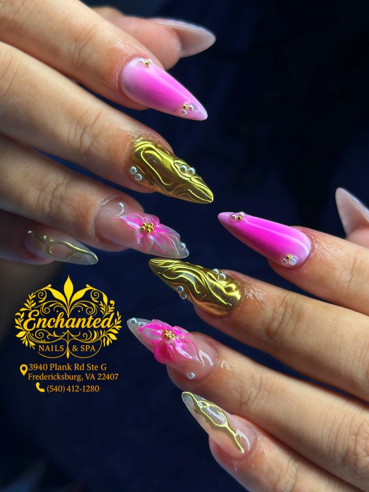 Elegant pink and gold stiletto nails with floral and pearl accents.