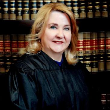 A woman judge posing in front of law books.