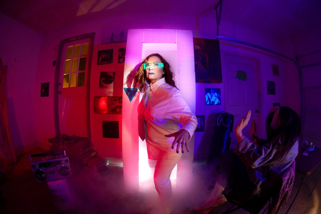 Woman in neon lights with futuristic glasses in a vibrant room.