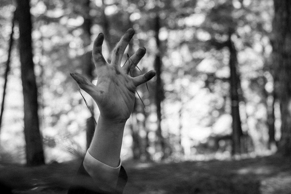 A hand reaching up outdoors in black and white.