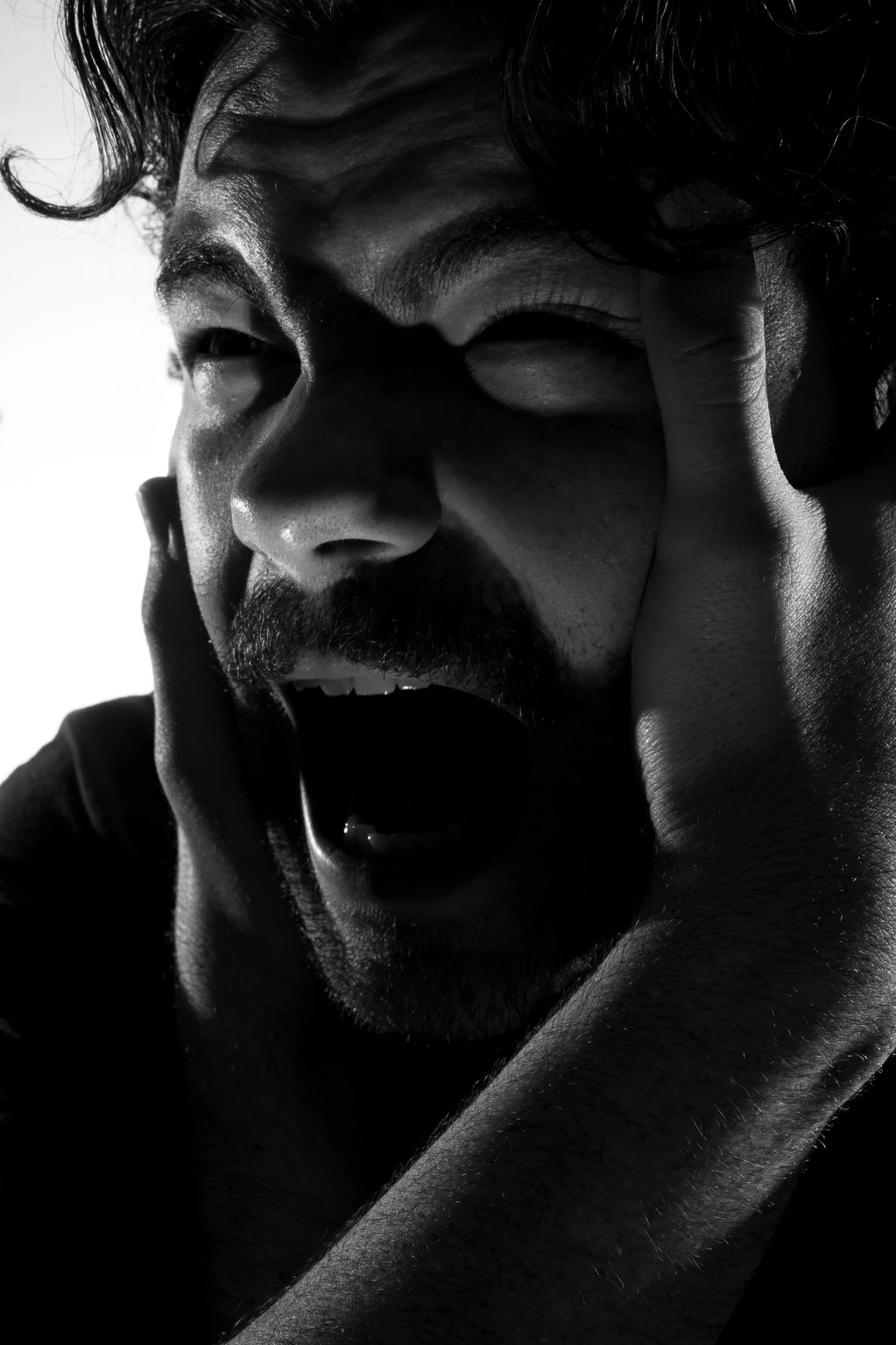 Man showing intense distress or anguish in black and white.