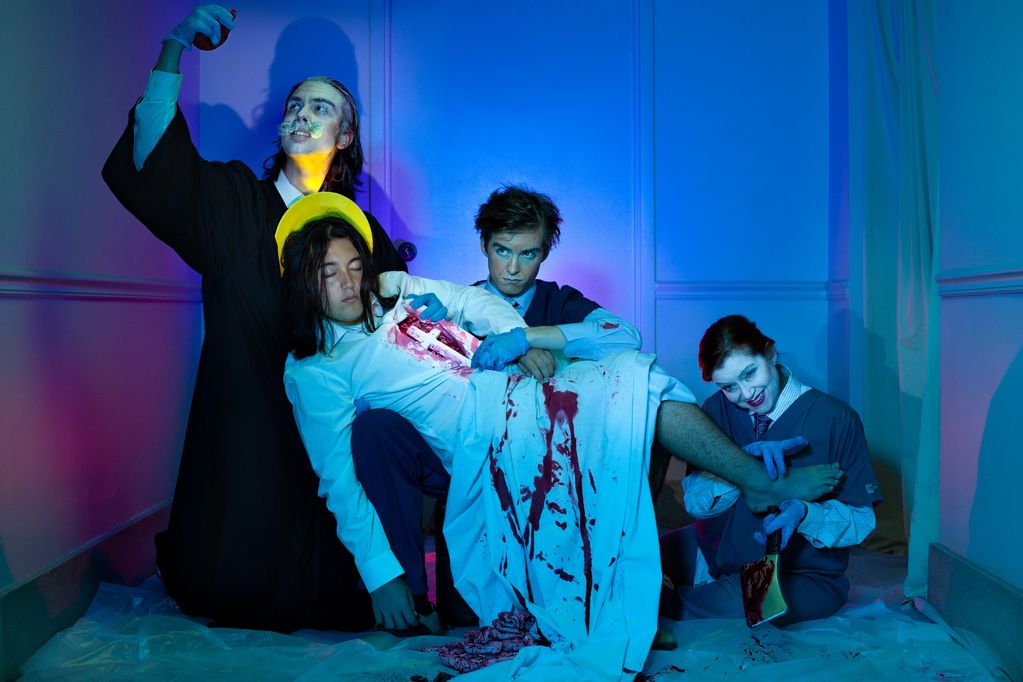 Four people in theatrical costumes with blood and blue gloves.