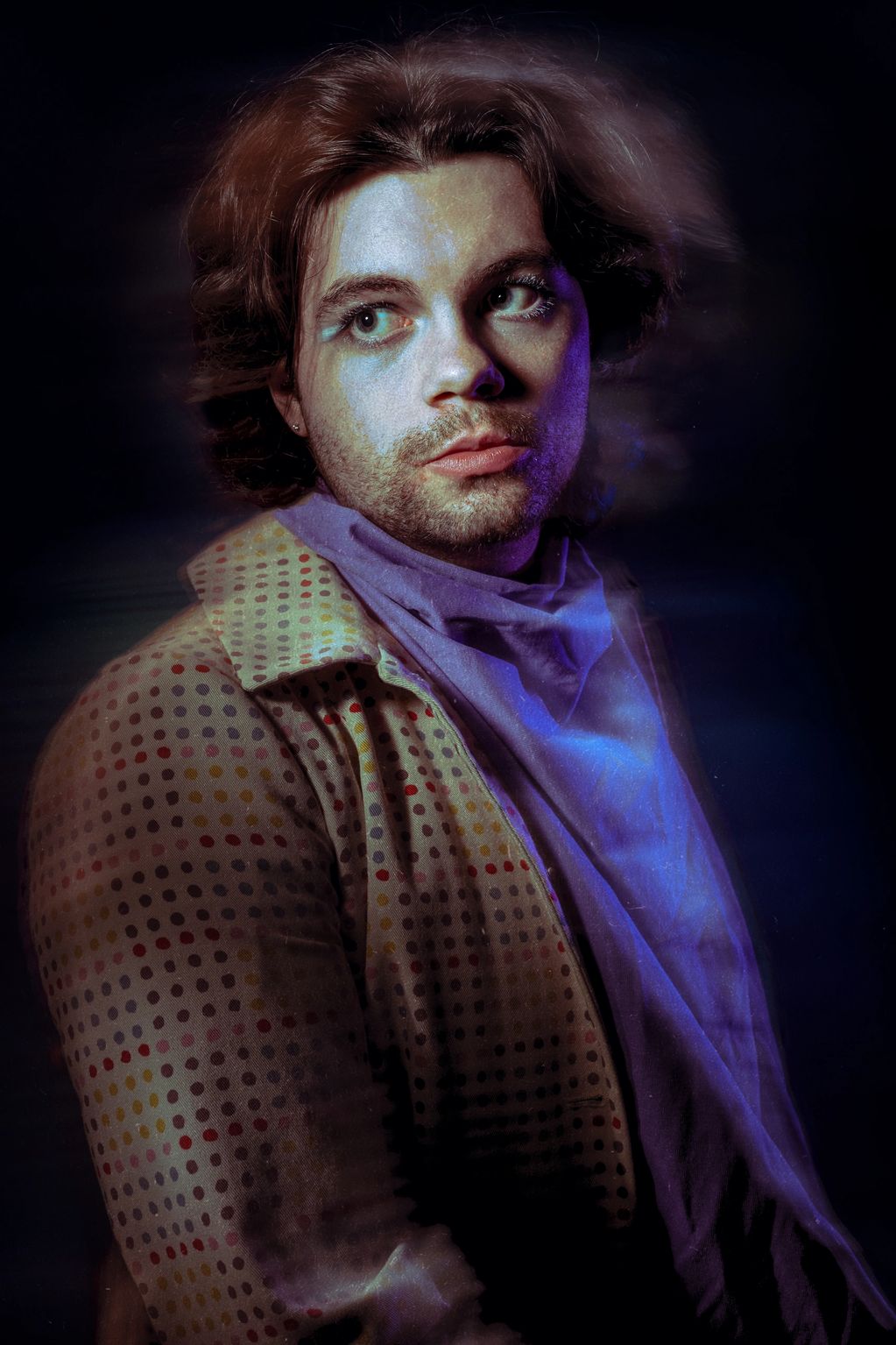Portrait of a young man in retro polka-dot jacket with dramatic lighting and purple hues.