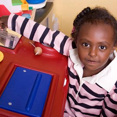 Young girl playing at a red activity table.