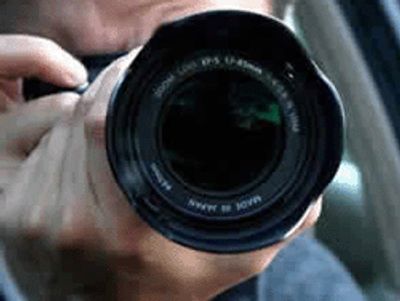 A private investigator using a camera to take images from his car during a surveillance operation. 