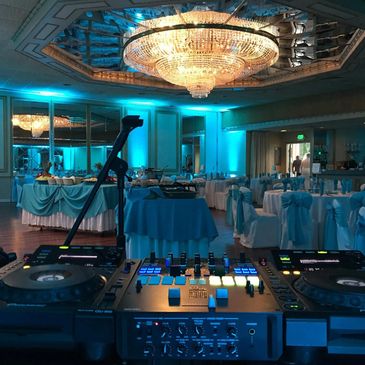 DJ setup with banquet tables in blue-lit room.