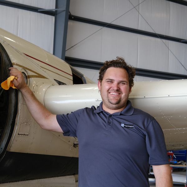 Man smiling next to an airplane engine.