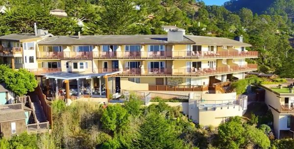 A large yellow hotel on a hillside surrounded by greenery.