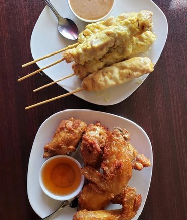 Chicken skewers with peanut sauce and crispy fried chicken wings with dipping sauce.