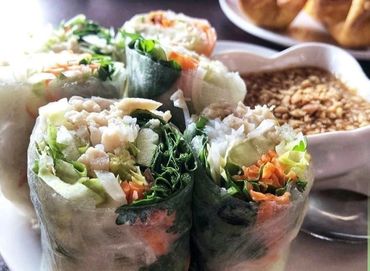 Fresh Vietnamese spring rolls with dipping sauce on a white plate.