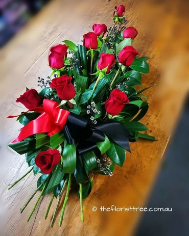 Red rose funeral flowers in a casket sheaf created by a qualified florist