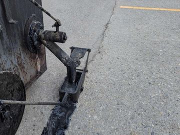 Applying Hot Rubber Pour Crack Fill to seal open cracks in lot for preventative pavement maintenance