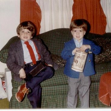 Boys in suits sitting on a green couch.