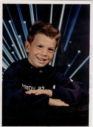 Smiling boy against dark blue background.