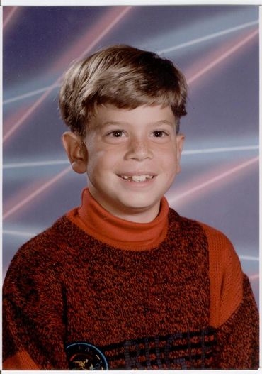 Young boy wearing orange turtleneck sweater.