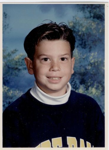 Young boy posing against blue background.