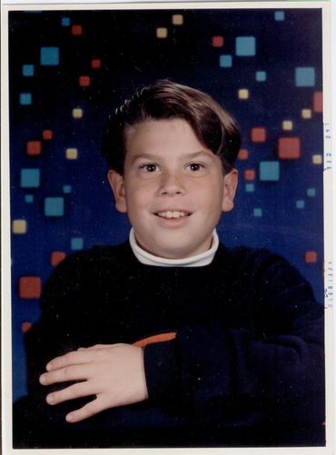 Boy in black sweater posing smiling.