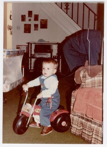 Toddler riding small tricycle indoors.