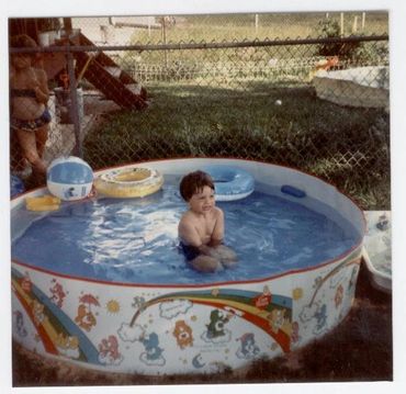 Young boy playing in plastic pool.