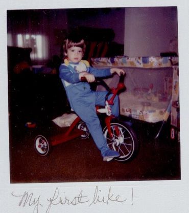 Young child riding a red tricycle.