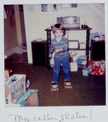 Toddler standing indoors on roller skates.