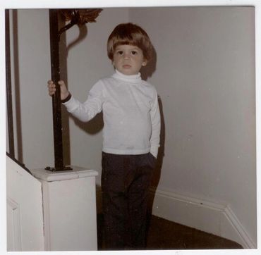 Young boy standing near a staircase.