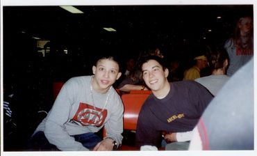 Two teenage boys sitting and smiling.