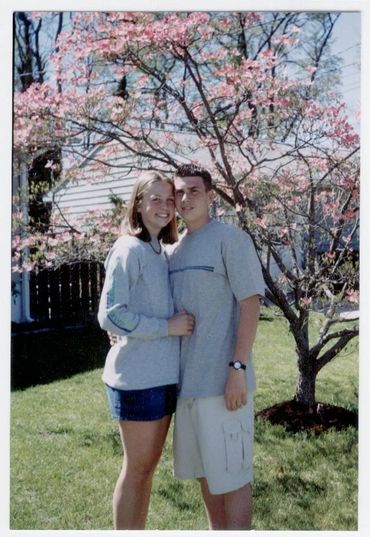 Couple posing by a flowering tree.