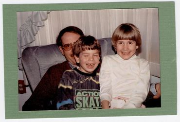 Two children sitting with an adult man.