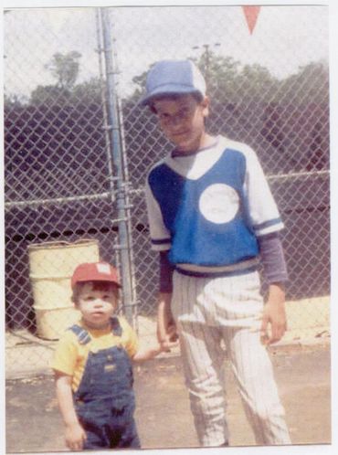 Two boys posing in front of fence.