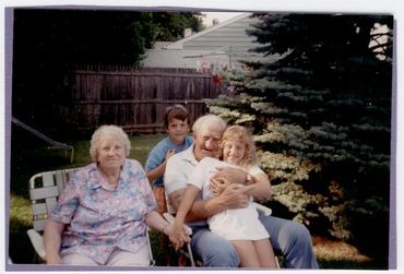 Grandparents sitting outside with their young grandchildren.