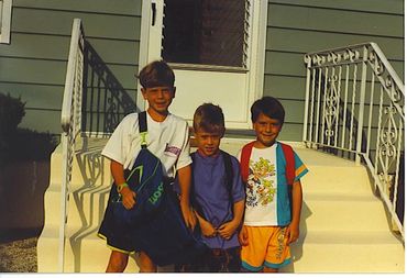 Three boys posing on porch steps.
