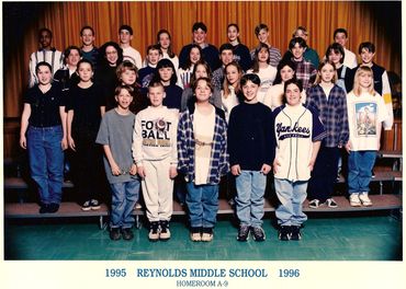 Middle school students posing on bleachers.