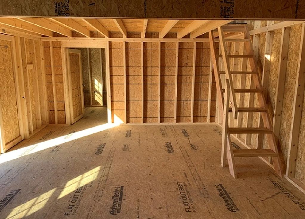 Interior of a wooden frame house under construction with a staircase.