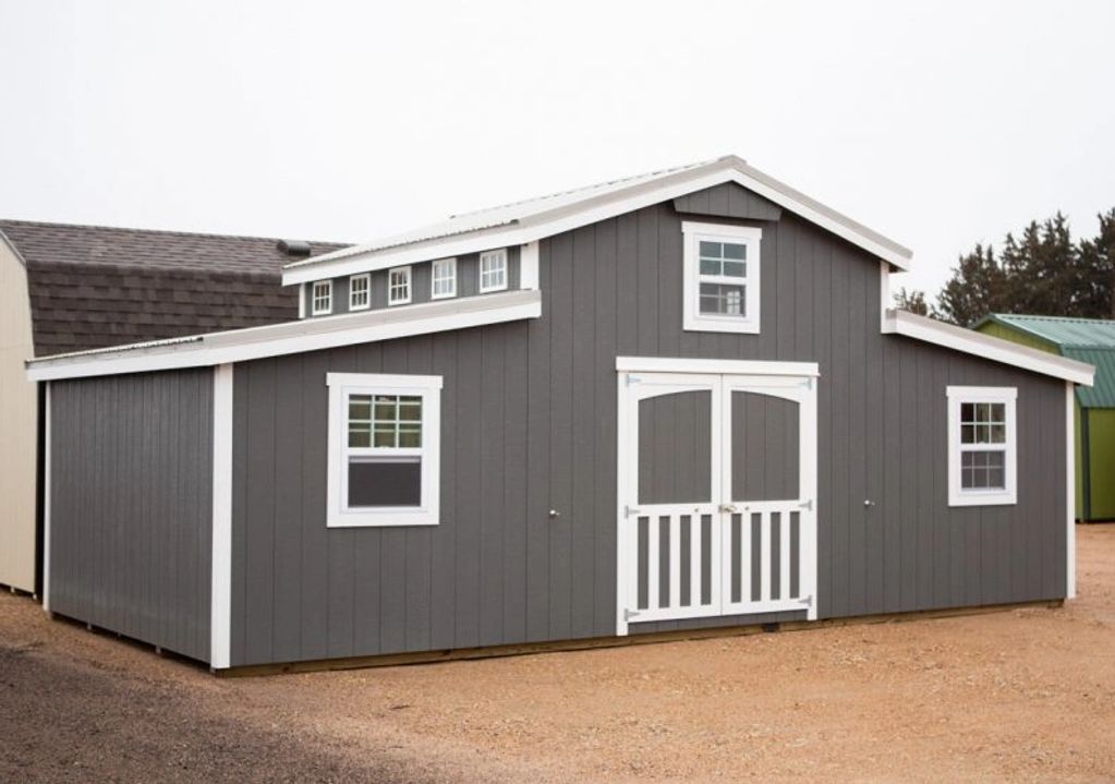 Gray barn-style shed with white trim and multiple windows.