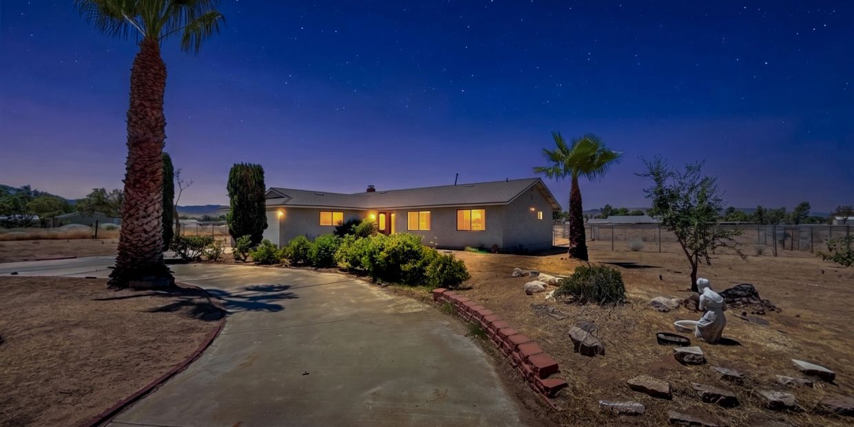 House at night with lit windows and starry sky.