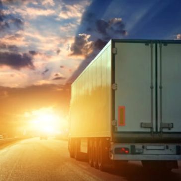 Truck driving into the sunset on an open road.