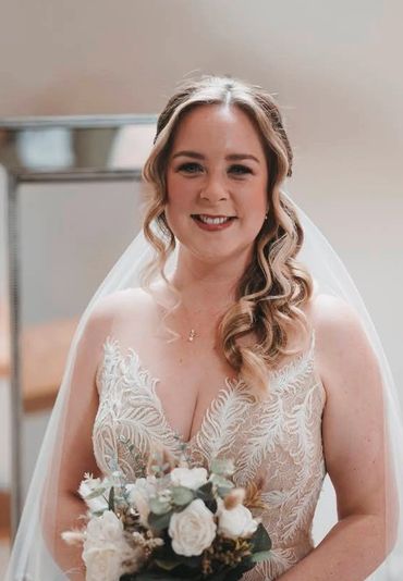 Bride smiling in a wedding dress holding a bouquet.
