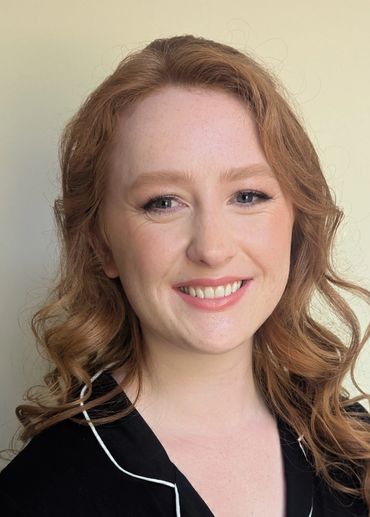 Smiling red-haired woman with curled hair.