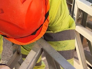 Construction worker in safety gear working with metal structures.