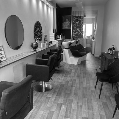 Modern hair salon with styling chairs and washing stations.