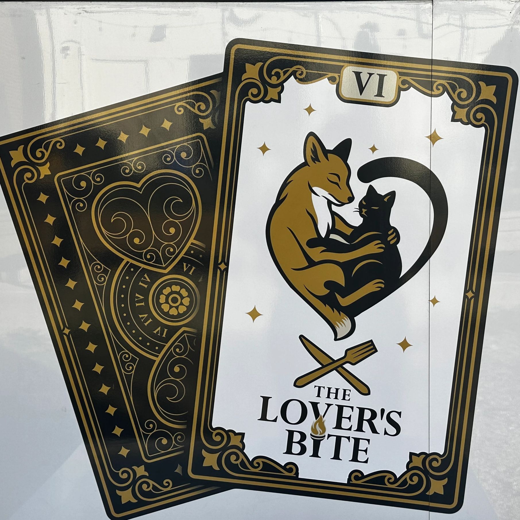Tarot card design featuring a fox and cat embracing, titled 'The Lover's Bite'.