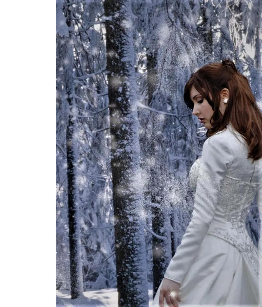 Lady in wedding dress showing off her engagement ring in the snowy woods