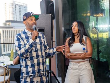 Man speaking into microphone while woman listens.