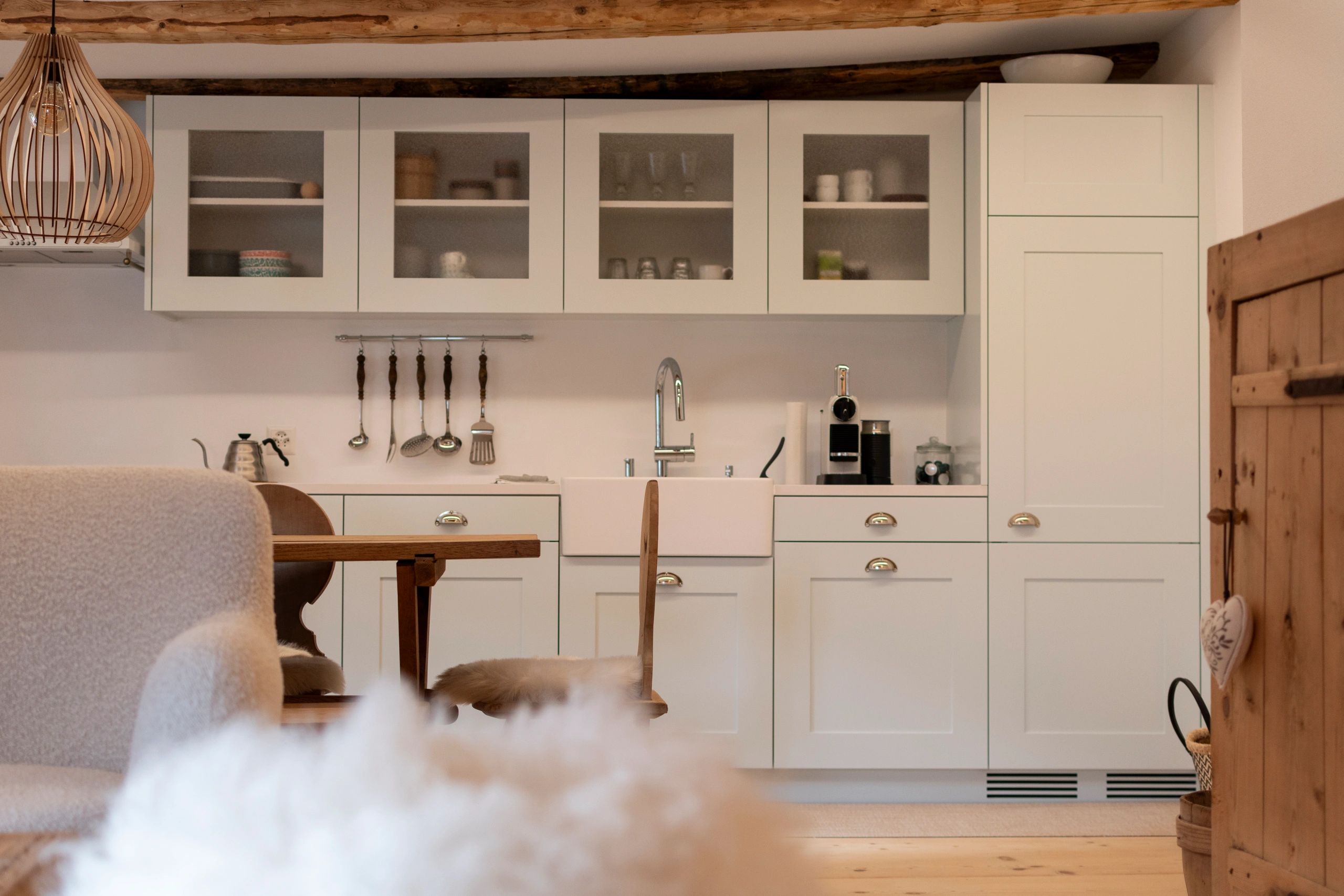 Cozy rustic kitchen with wooden beams and white cabinets.